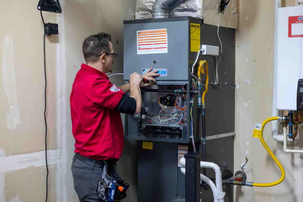 HVAC technician performing precision tune-up on modern furnace - how a maintenance plan extends equipment life